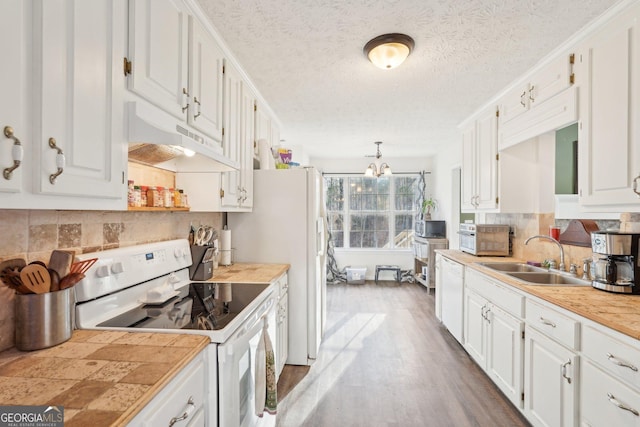 kitchen with white cabinetry, sink, hanging light fixtures, and white appliances