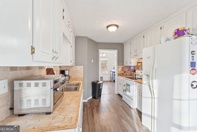 kitchen with white cabinetry, light hardwood / wood-style flooring, tile countertops, a textured ceiling, and white appliances