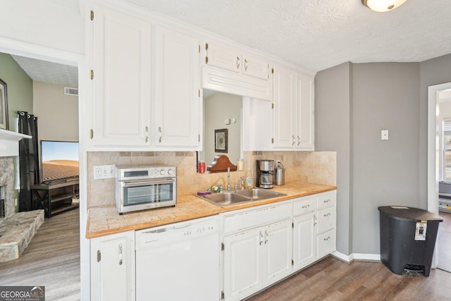 kitchen featuring white dishwasher, wood-type flooring, white cabinetry, and sink