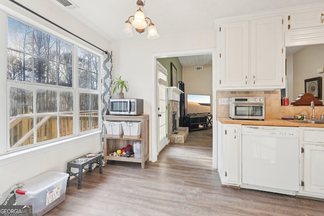 kitchen featuring tasteful backsplash, light hardwood / wood-style floors, dishwasher, a chandelier, and white cabinetry