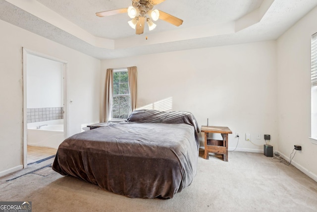 bedroom featuring connected bathroom, ceiling fan, a raised ceiling, light colored carpet, and a textured ceiling