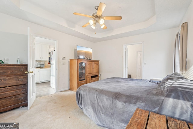 carpeted bedroom with ceiling fan, ensuite bath, and a tray ceiling