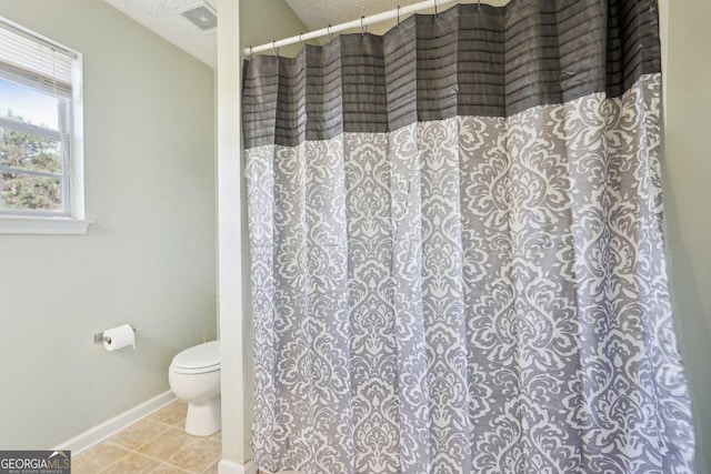 bathroom with tile patterned floors, a shower with curtain, toilet, and a textured ceiling