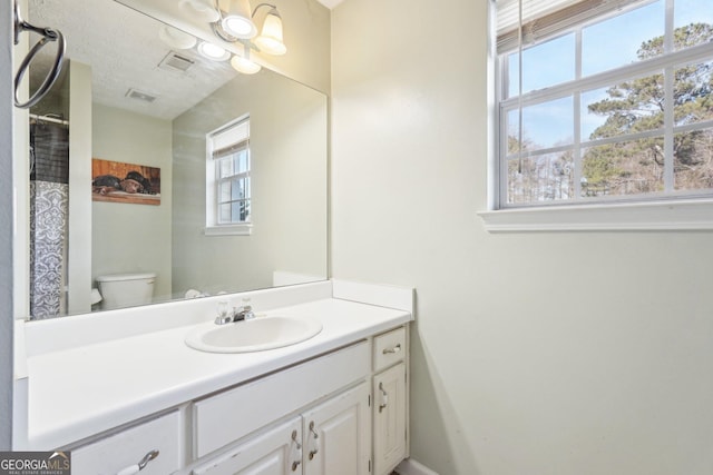 bathroom with a textured ceiling, vanity, and toilet