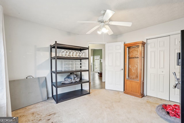 carpeted bedroom featuring ceiling fan, a closet, and a textured ceiling