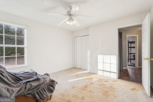 living area with ceiling fan, light carpet, and a textured ceiling