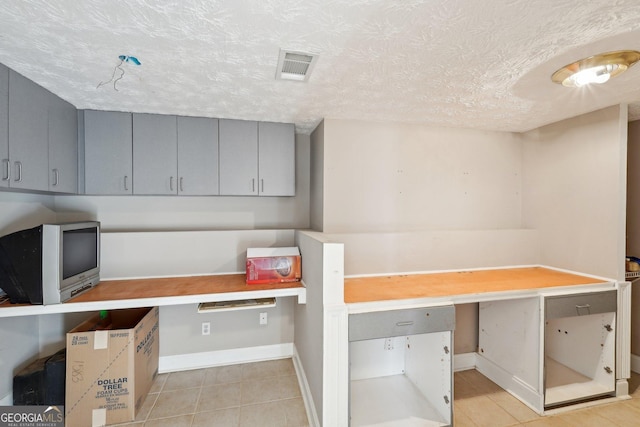 kitchen featuring a textured ceiling, built in desk, and gray cabinetry