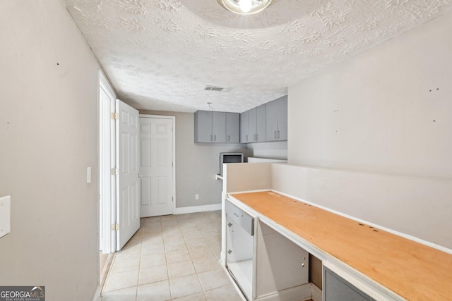 kitchen featuring a textured ceiling, gray cabinetry, and light tile patterned flooring