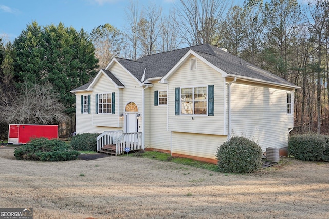 bi-level home with cooling unit and a front yard