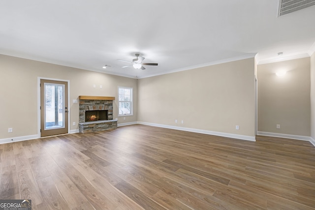 unfurnished living room featuring ceiling fan, ornamental molding, a fireplace, and hardwood / wood-style floors