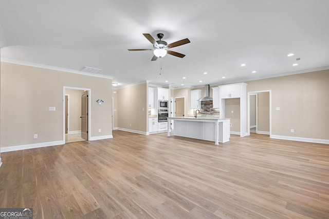 unfurnished living room featuring crown molding, ceiling fan, sink, and light hardwood / wood-style floors