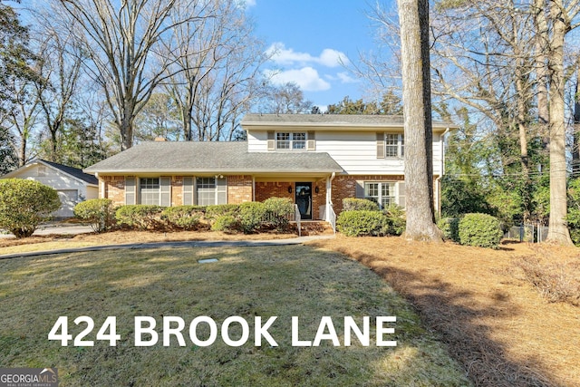 traditional home featuring a front yard and brick siding