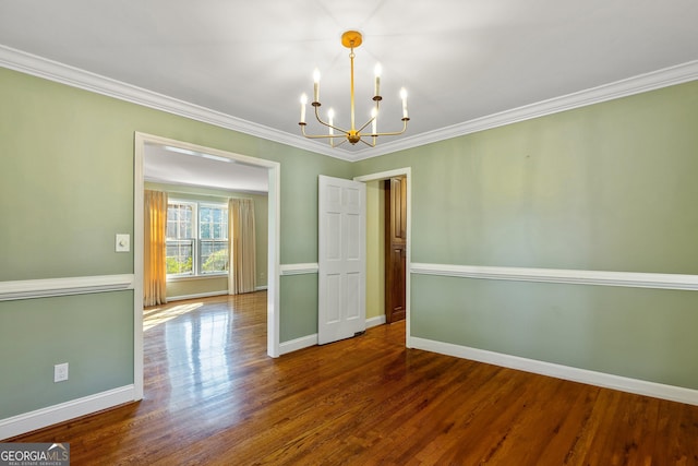 empty room featuring dark hardwood / wood-style flooring, crown molding, and a chandelier