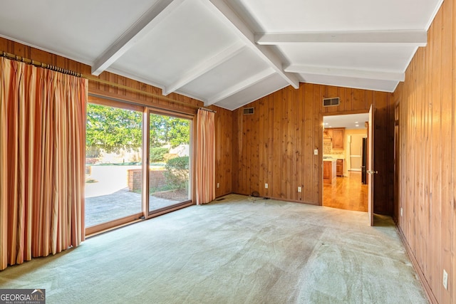 unfurnished room featuring light carpet, wooden walls, visible vents, and lofted ceiling with beams