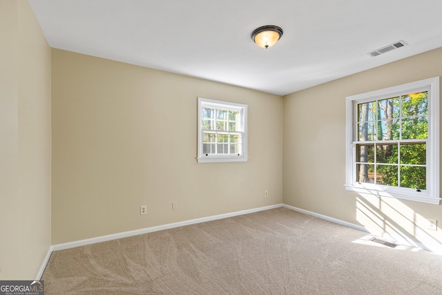 carpeted spare room featuring visible vents and baseboards