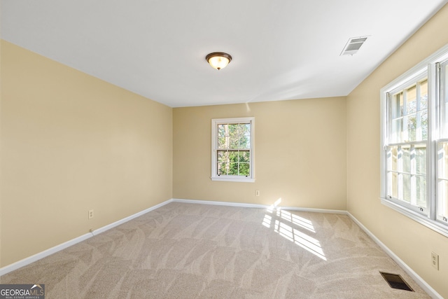 empty room with light colored carpet and a healthy amount of sunlight