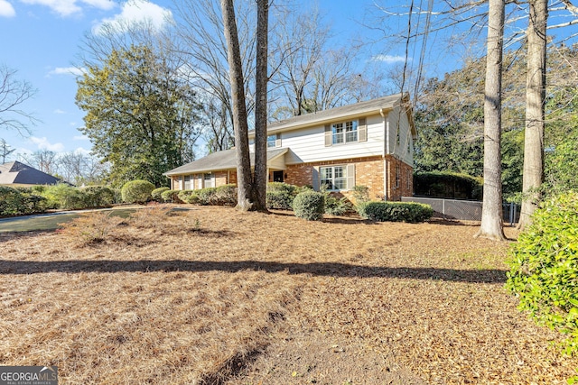 view of front of home featuring fence and brick siding