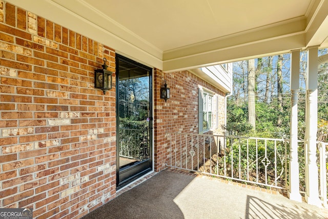 entrance to property featuring a porch and brick siding