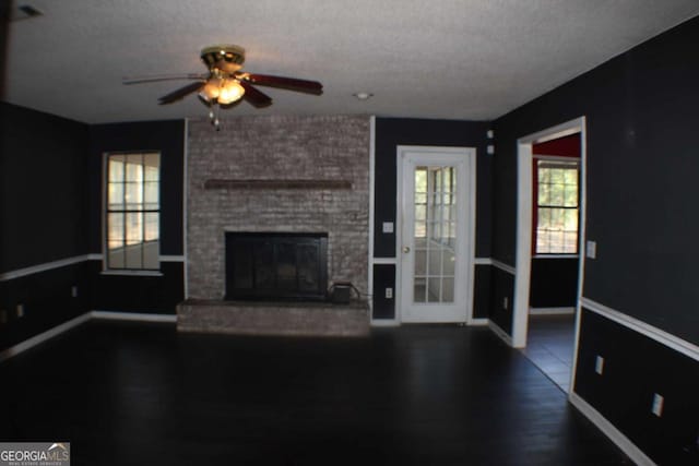 unfurnished living room with ceiling fan, a textured ceiling, and a brick fireplace