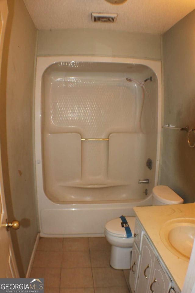 bathroom featuring tile patterned flooring, vanity, a textured ceiling, and toilet