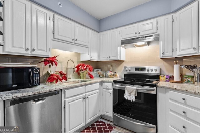 kitchen featuring tasteful backsplash, white cabinetry, appliances with stainless steel finishes, and light stone counters