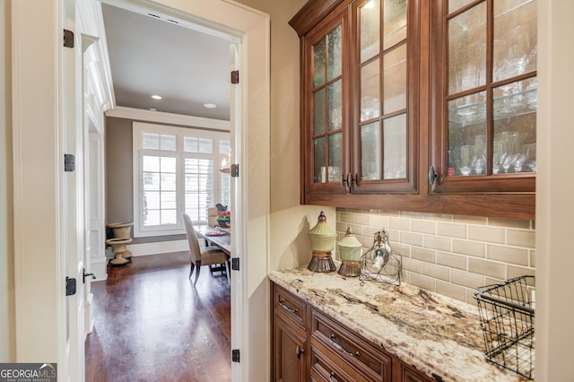 bar featuring dark hardwood / wood-style floors, decorative backsplash, and light stone countertops