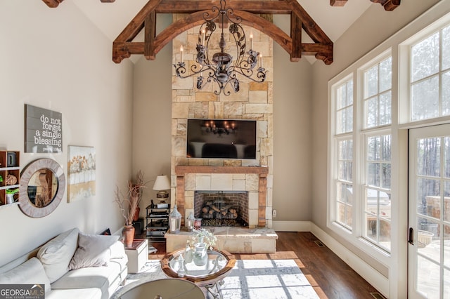 living room with dark wood-type flooring, a stone fireplace, high vaulted ceiling, beamed ceiling, and a notable chandelier