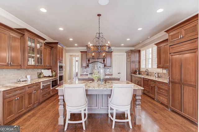 kitchen featuring decorative backsplash, decorative light fixtures, a kitchen island with sink, and dark wood-type flooring