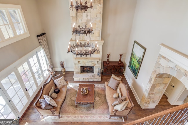 living room featuring a stone fireplace, a towering ceiling, and a chandelier