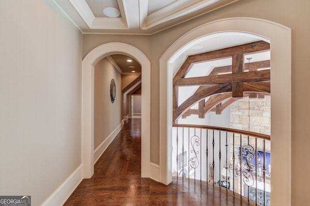 hallway with beamed ceiling, ornamental molding, and dark wood-type flooring