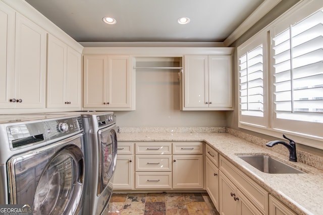 clothes washing area featuring cabinets, washing machine and dryer, and sink