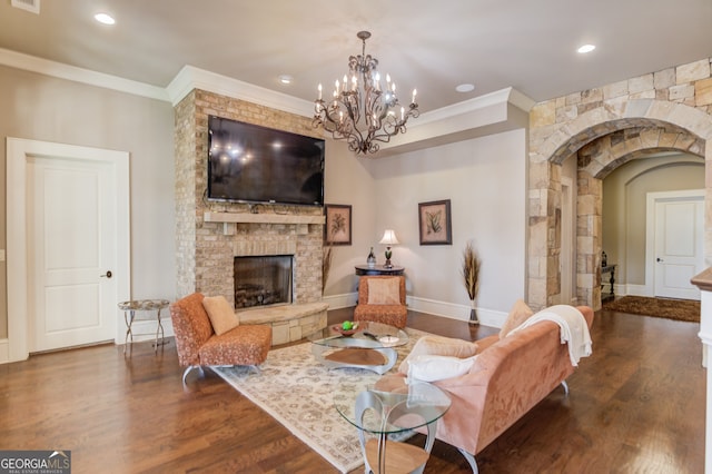 living room featuring a fireplace, dark hardwood / wood-style flooring, a chandelier, and ornamental molding