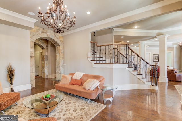 living room featuring ornate columns, a chandelier, dark wood-type flooring, and ornamental molding