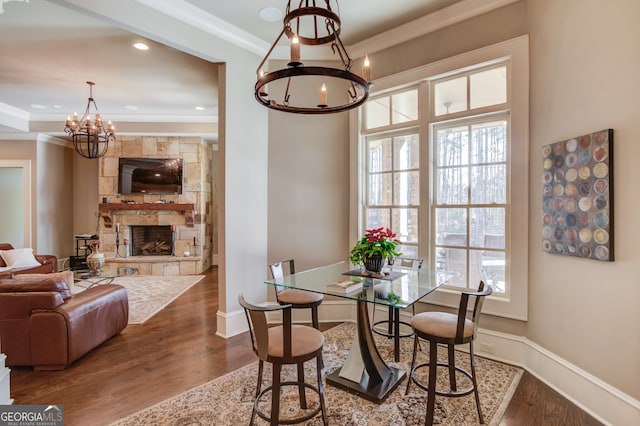 dining area featuring hardwood / wood-style floors, crown molding, a fireplace, and a chandelier