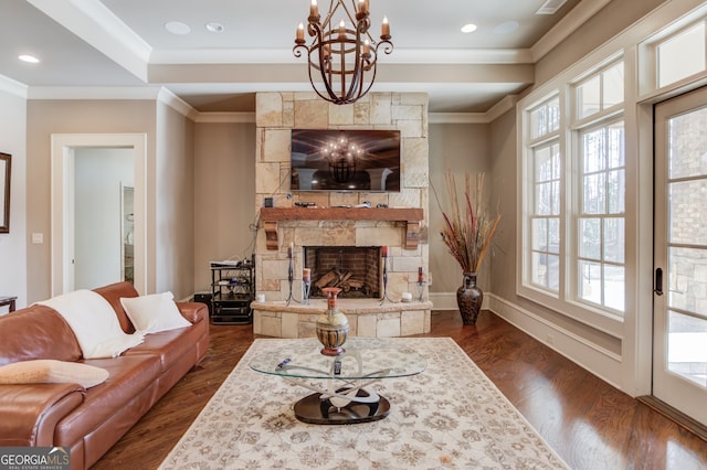 living room featuring dark hardwood / wood-style flooring, a fireplace, ornamental molding, and a notable chandelier