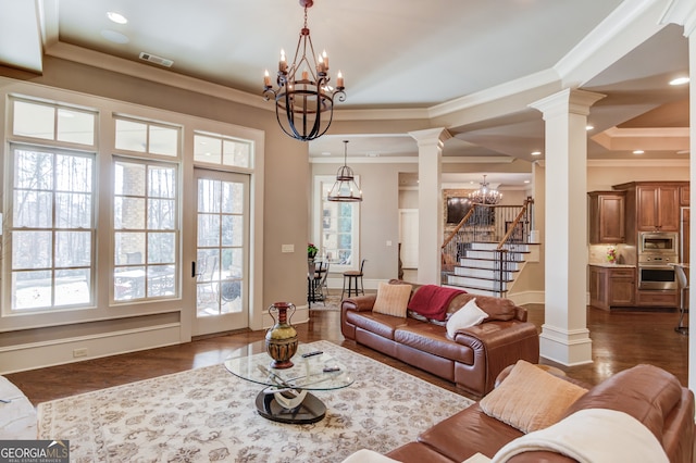 living room featuring a notable chandelier, dark hardwood / wood-style floors, crown molding, and decorative columns