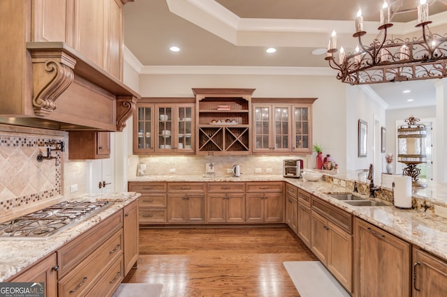 kitchen with light stone countertops, tasteful backsplash, stainless steel gas cooktop, sink, and a chandelier