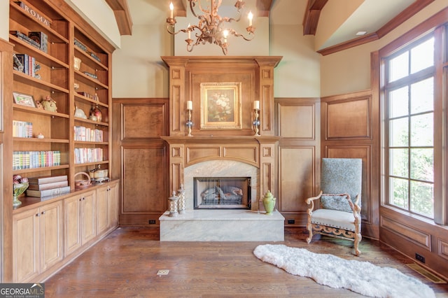 living area with a fireplace, built in shelves, dark hardwood / wood-style flooring, and wooden walls