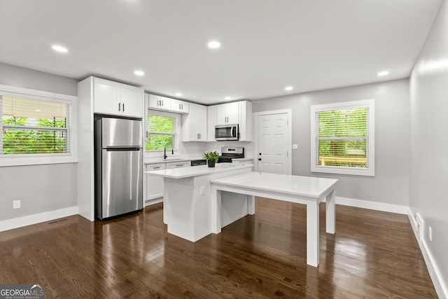 kitchen featuring sink, appliances with stainless steel finishes, dark hardwood / wood-style floors, a kitchen island, and white cabinets