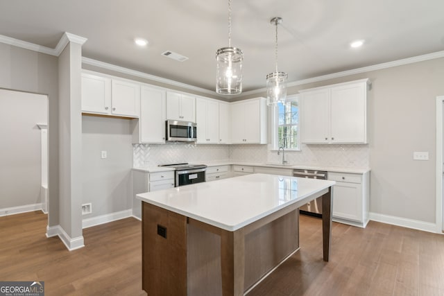 kitchen with ornamental molding, appliances with stainless steel finishes, dark wood finished floors, and white cabinets