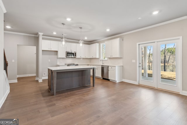 kitchen with stainless steel appliances, wood finished floors, backsplash, and white cabinets