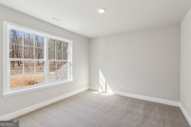 spare room featuring carpet flooring, visible vents, and baseboards