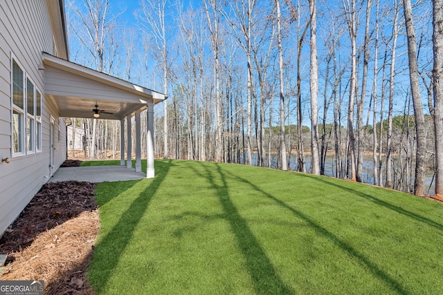 view of yard with a patio area, a ceiling fan, and a water view