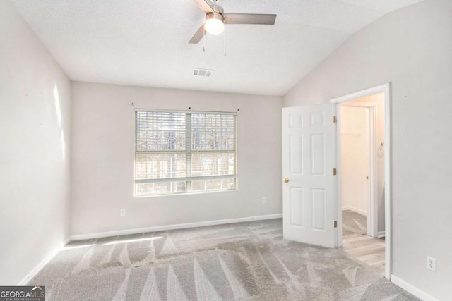 carpeted spare room featuring a textured ceiling, ceiling fan, and lofted ceiling