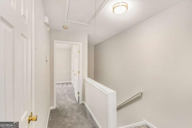 corridor with light carpet and a textured ceiling