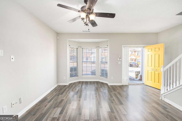 interior space with a textured ceiling, ceiling fan, and dark wood-type flooring