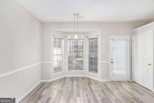 unfurnished dining area with a textured ceiling and light hardwood / wood-style flooring