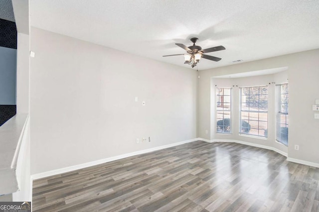 spare room with a textured ceiling, ceiling fan, and dark wood-type flooring