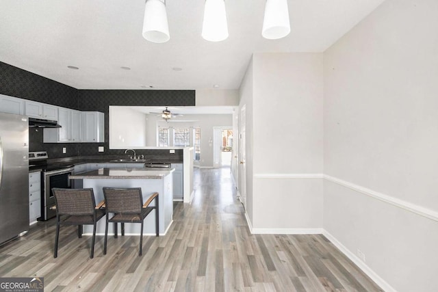 kitchen with white cabinets, decorative light fixtures, kitchen peninsula, and stainless steel appliances