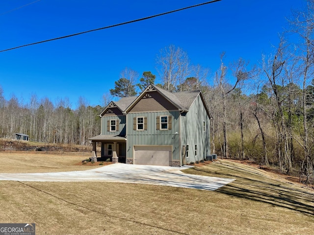 view of front of house with an attached garage, concrete driveway, stone siding, board and batten siding, and a wooded view